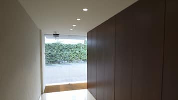 A modern hallway with a polished floor, recessed ceiling lights, and a view of a paved area and greenery outside.