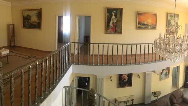 A multi-level interior with a grand staircase, chandeliers, and artwork on the walls. - The luxurious private house in Yerevan, Armenia (Erebuni)