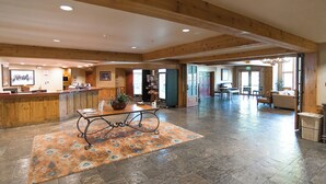 A spacious lobby with a reception desk, a coffee table, and a dining area with chairs and tables.