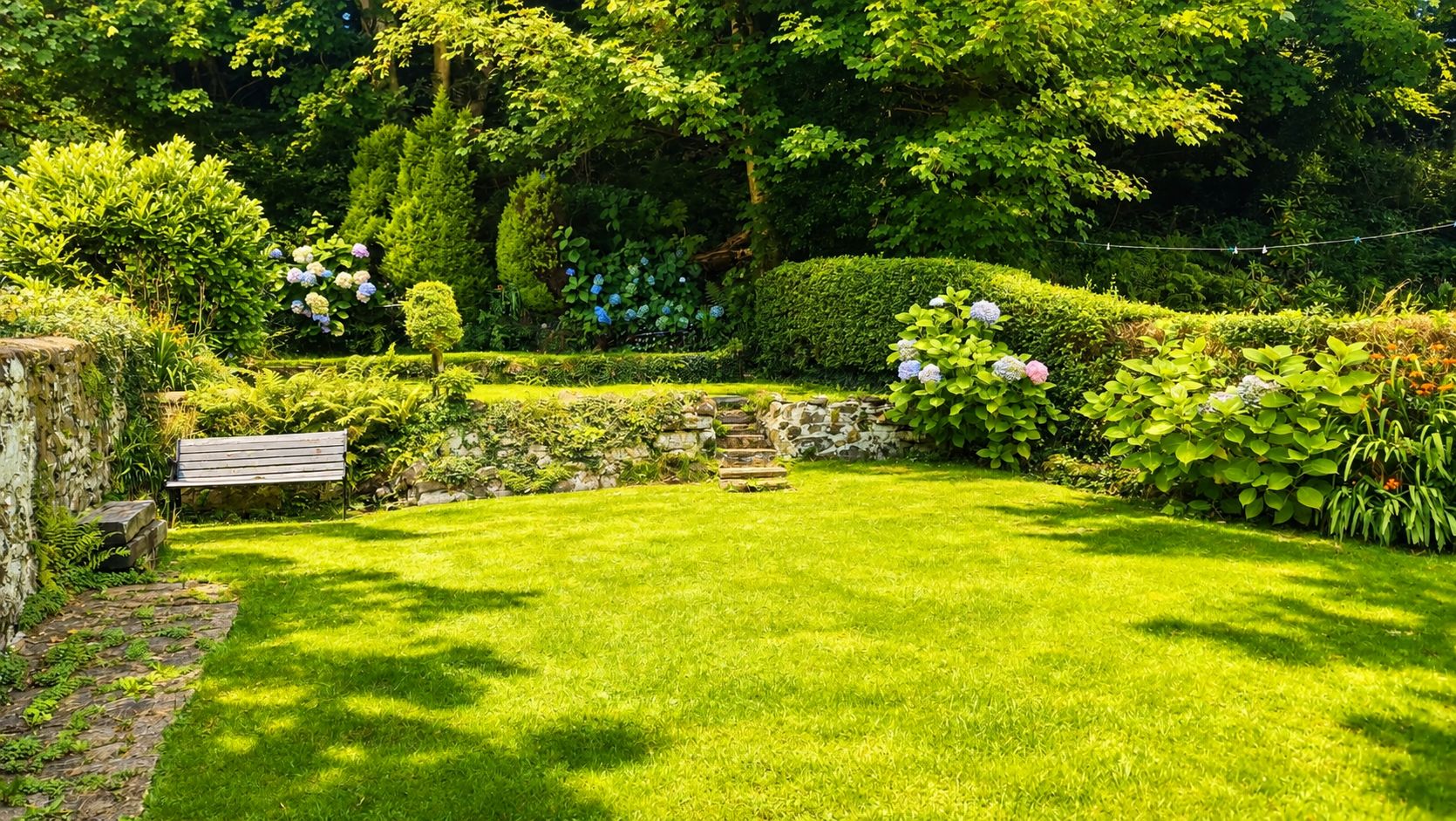 Un jardin bien entretenu, avec une pelouse, un mur en pierre et un banc en bois.