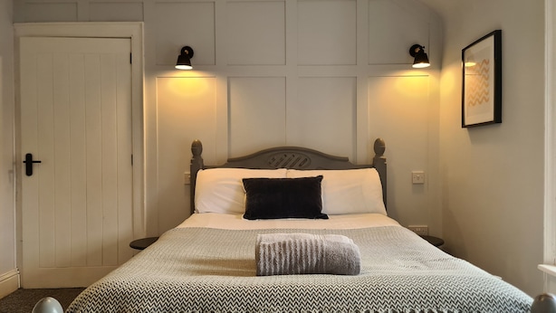A neatly made bed with a patterned bedspread, two bedside lamps, and a framed picture on the wall.