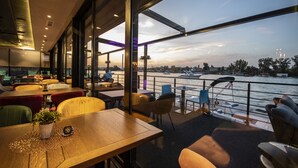 A restaurant with a view of the river, featuring tables and chairs arranged for dining. - Flow (Belgrade)