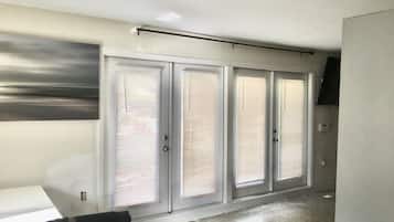 A hallway with four doors, a ceiling light, and a wall-mounted television.
