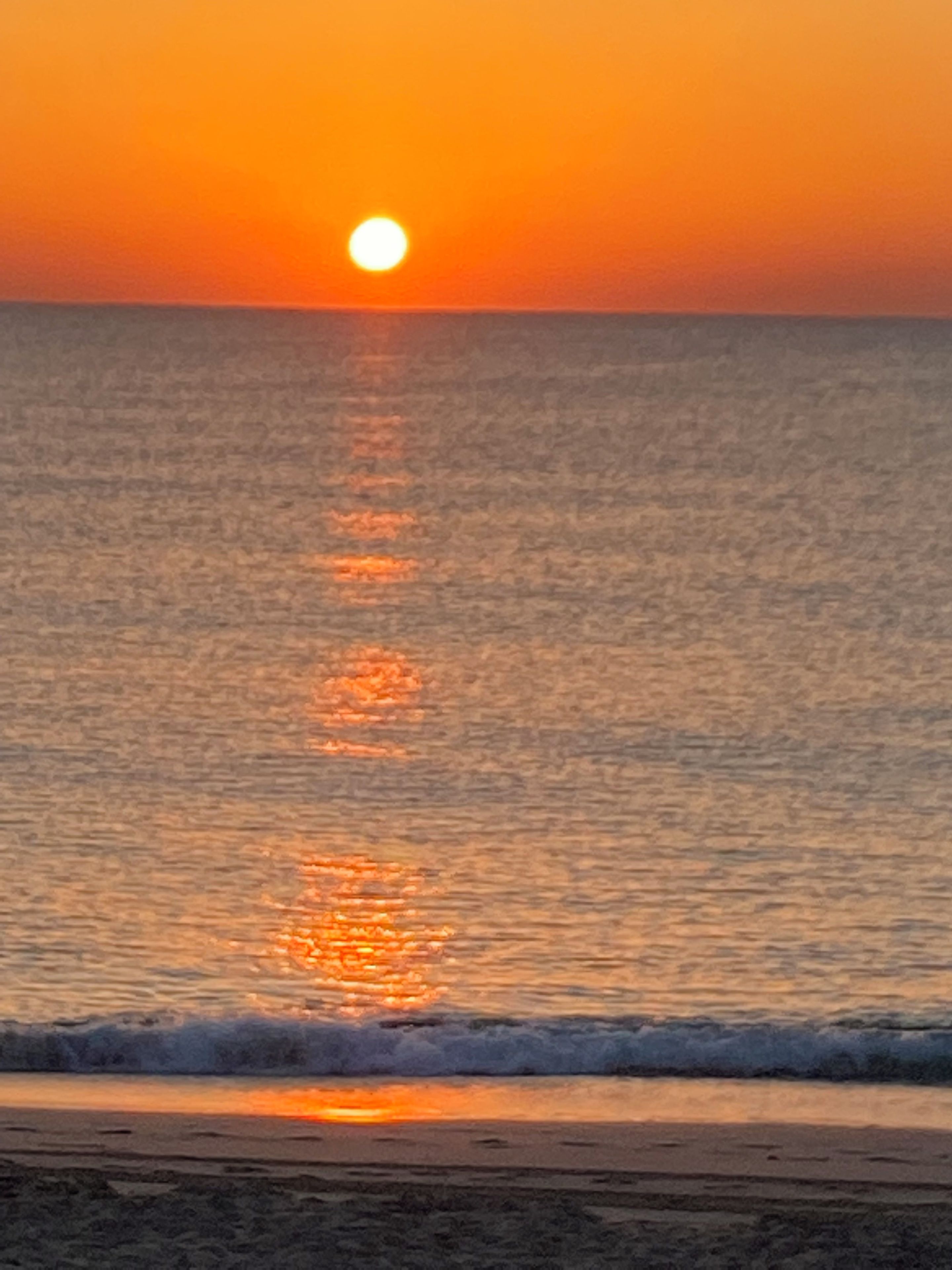 A sunset over a calm sea with gentle waves.
