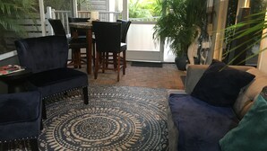 Een gezellige zithoek met een kamerkleed, een bank en een eettafel met stoelen.