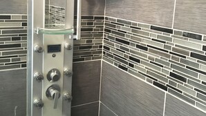 Een moderne douche met glazen wanden en bedieningspaneel.