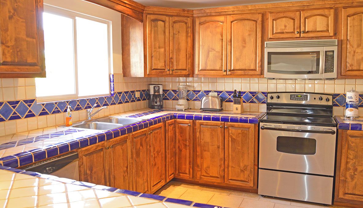 A kitchen with wooden cabinets, a stainless steel oven, a microwave, and a sink.