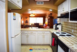 Kitchen features a refrigerator, stove, and sink, with a window above the sink.