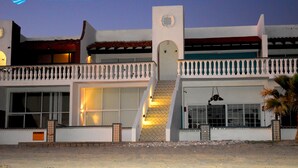 A two-story building with a balcony, large windows, and a staircase leading to the upper level.