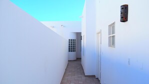 A narrow, tiled corridor with white walls and a door at the end.