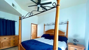A four-poster bed with a wooden frame and a ceiling fan.