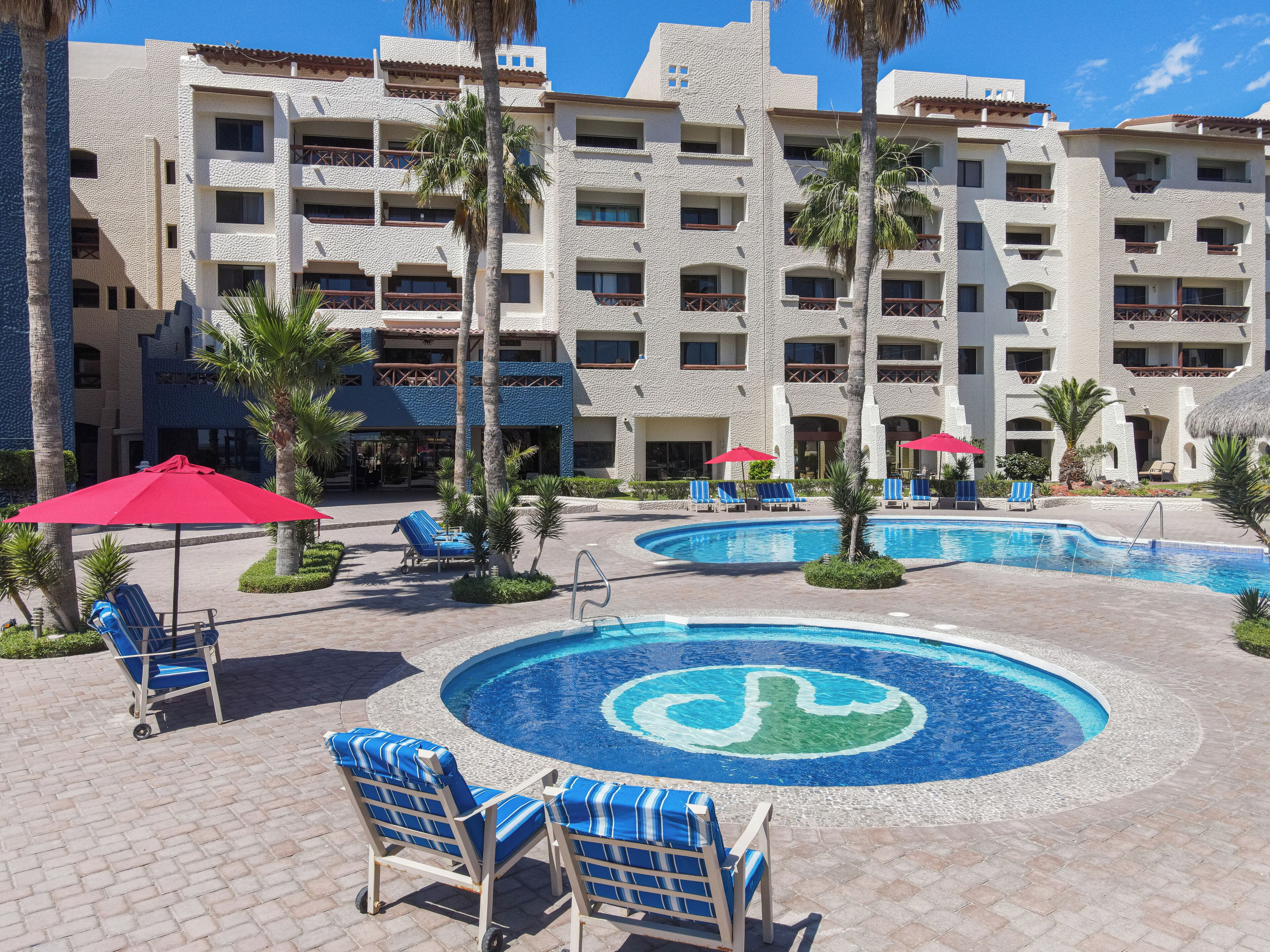 A resort with multiple swimming pools, lounge chairs, and palm trees.