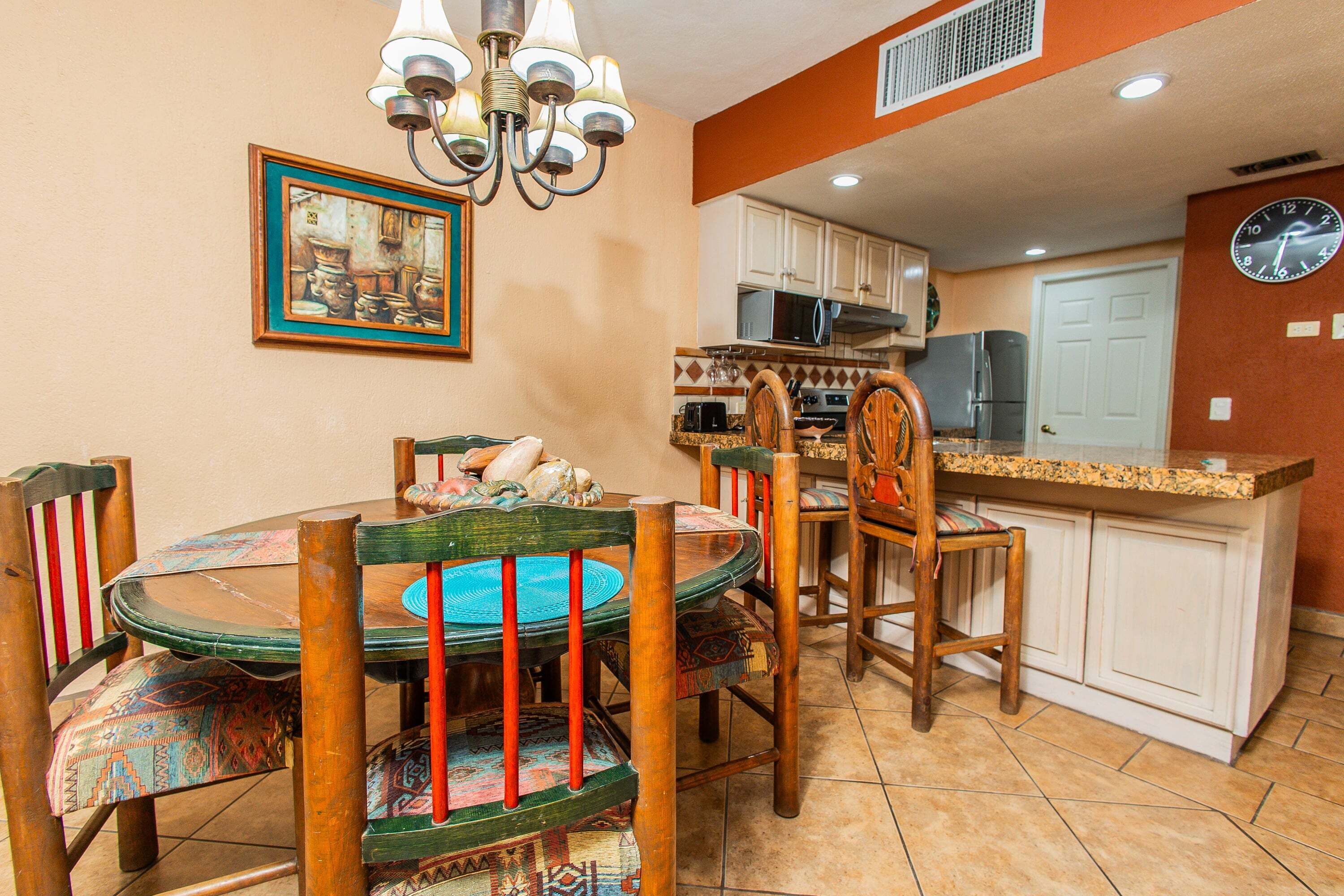 A dining area with a round table, chairs, and a chandelier.