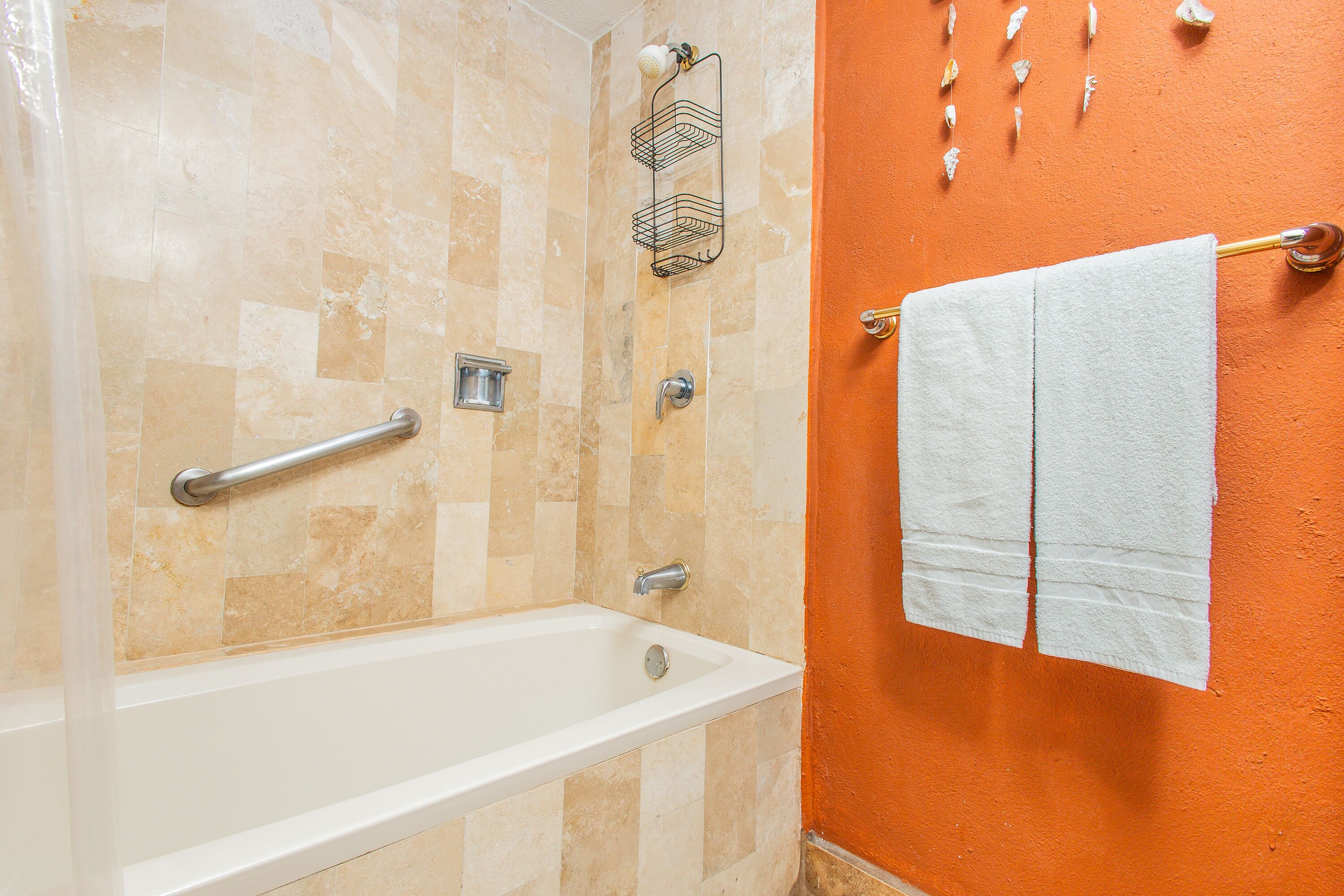 A bathroom with a bathtub, a shower, and a towel rack with towels.