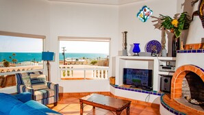 Een woonkamer met uitzicht op zee, een open haard en een televisie.