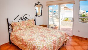 Een slaapkamer met een bed, een klein tafeltje, een spiegel en een schuifdeur naar een buitenruimte.