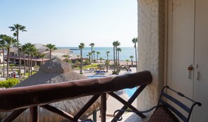 Een balkon met uitzicht op een resort, inclusief een zwembad en palmbomen.