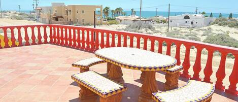 Une terrasse dotée d’une rambarde rouge, d’une table ronde et de deux bancs.