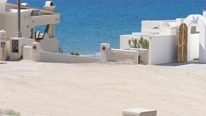 Ein Küstengebäude mit weißer Fassade, einem Holztor und Blick auf das Meer.