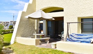 Enjoy outdoor seating on the patio with a table, chairs, and umbrella, surrounded by a well-maintained lawn.