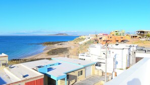A coastal view with buildings, a beach, and mountains in the distance.