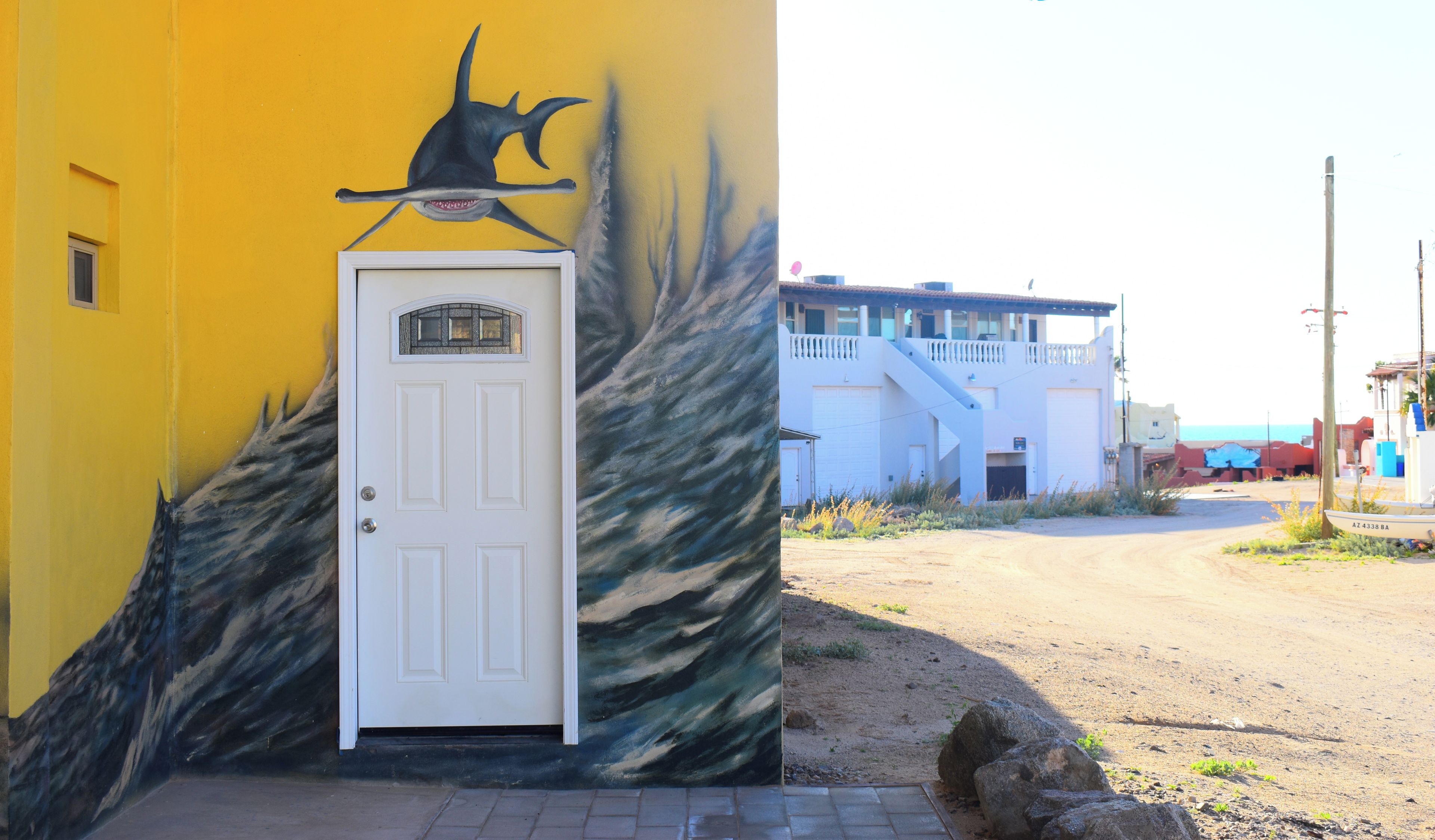 Un bâtiment avec une porte blanche et une fresque représentant un poisson sur le mur.