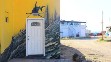 Un bâtiment avec une porte blanche et une fresque représentant un poisson sur le mur.