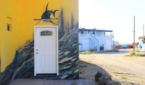 A building with a white door and a mural of a fish on the wall.