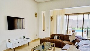A modern living room with a sofa, coffee table, and TV. - The Villa of Peace. (Marrakech)