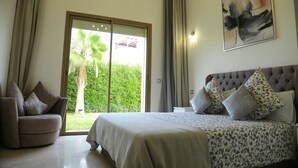 A bedroom with a bed, a sofa, a large window with curtains, and a painting on the wall. - The Villa of Peace. (Marrakech)