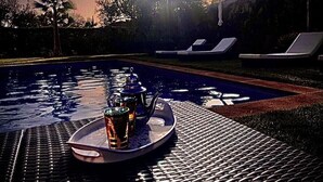 A poolside setting with lounge chairs, a tray with a beverage and a teapot, and a sunset in the background. - The Villa of Peace. (Marrakech)