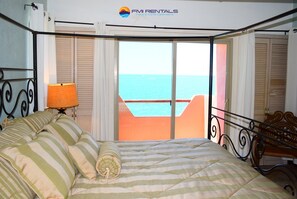 A bedroom with a bed, a nightstand, a lamp, and a view of the sea through a balcony. - Marina Pinacate B-307 Ocean View 2 Bed/ 2 Bath (Puerto Peñasco Centro)