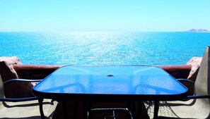A table and chairs facing a body of water with a logo and text indicating a rental service. - Marina Pinacate B-307 Ocean View 2 Bed/ 2 Bath (Puerto Peñasco Centro)