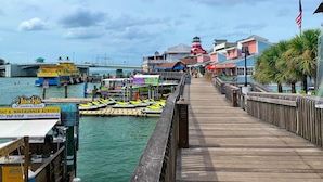 A pier with a view of a waterfront area, including a dock with boats and a sign for Jack's Boat & Waverunner Rentals.