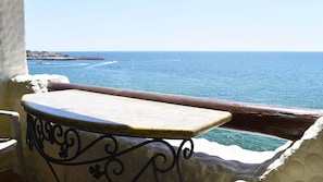 Enjoy a serene view of the coastline from this balcony with a small table and chair.