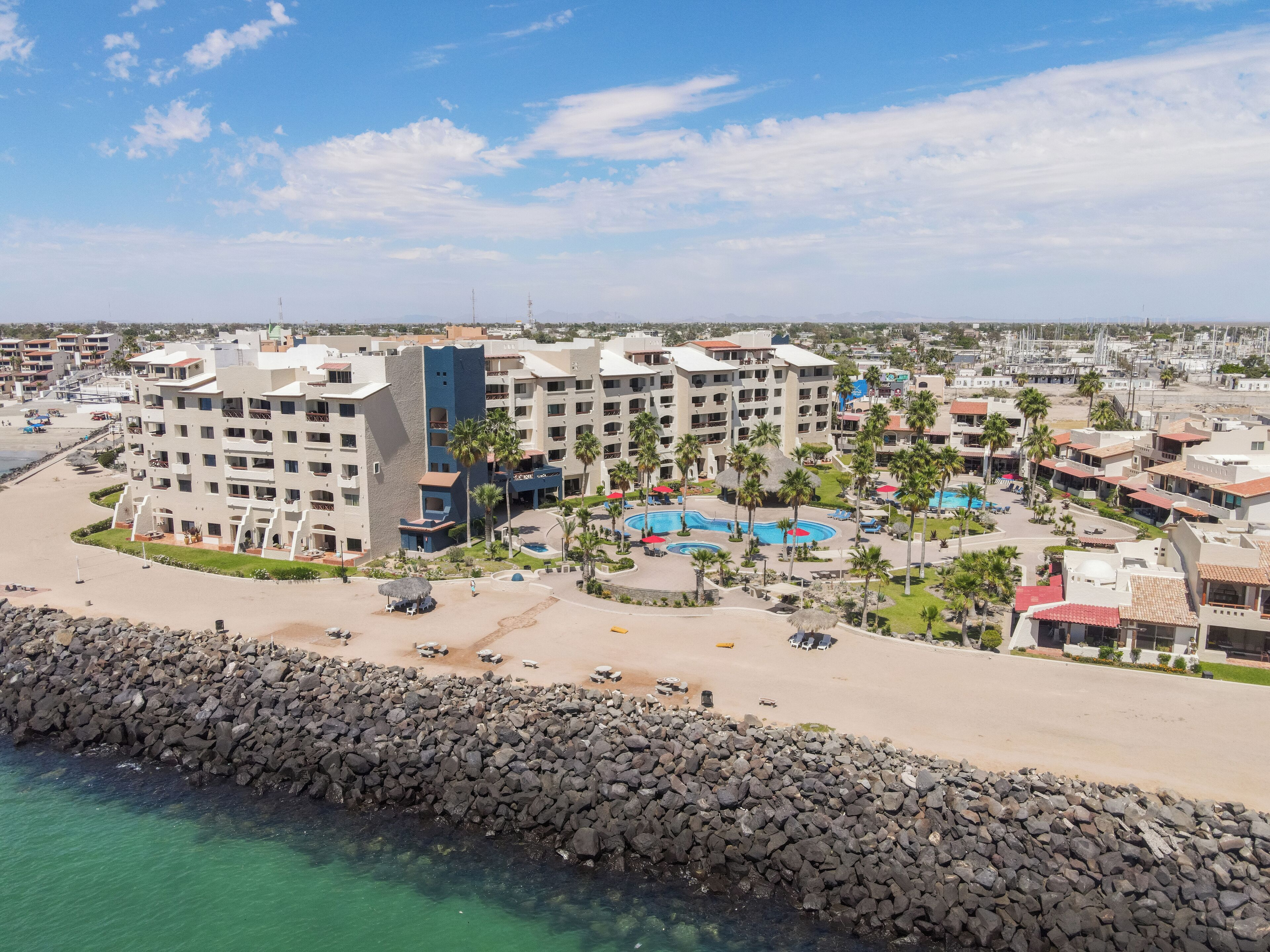 Un resort con varias construcciones, una playa y un litoral rocoso.