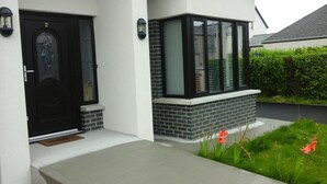 Une maison moderne avec une porte d’entrée noire, un petit porche et une fenêtre ornée d’une façade en briques.