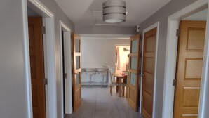 Un couloir avec des portes en bois, un coin cuisine avec des tabourets de bar et une table à manger avec des chaises.