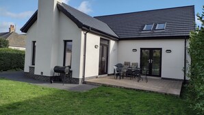 Une maison moderne dotée d’un patio, d’un barbecue et d’un espace salon.