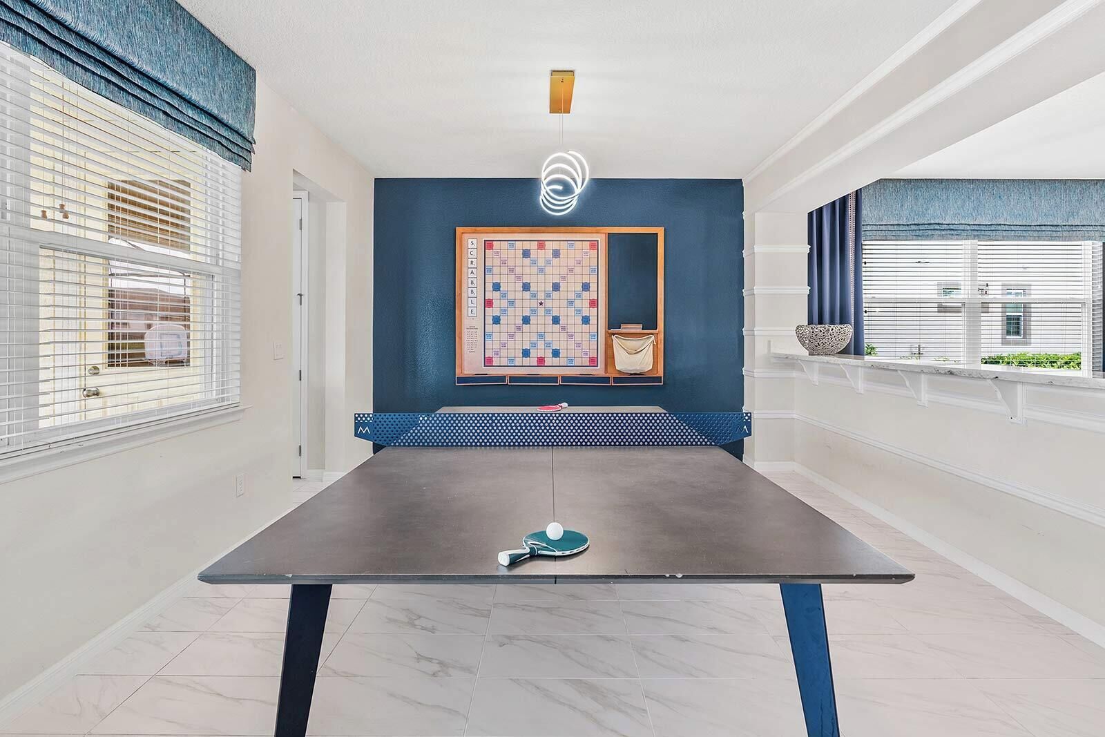 A room with a ping pong table, a blue accent wall, and a framed board game.
