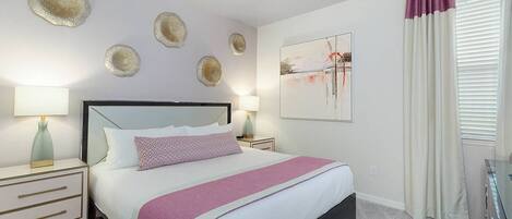 A modern bedroom with a large bed, two bedside tables, a ceiling fan, decorative wall art, and a window with curtains.