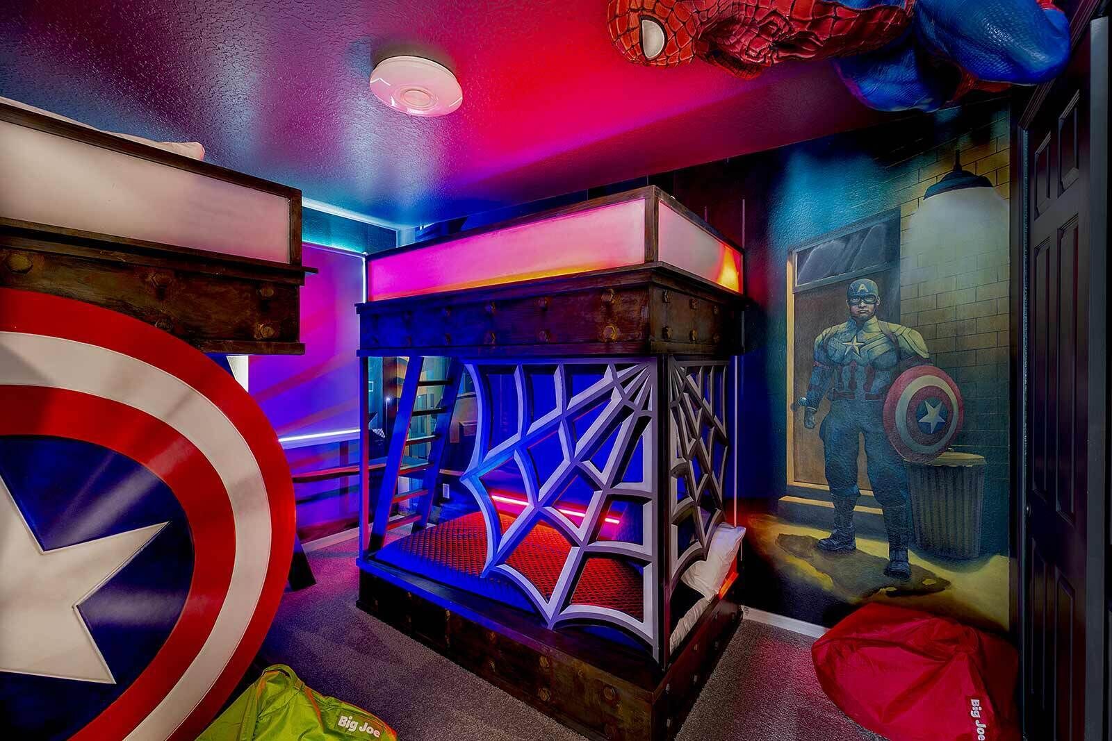 Una habitación con un escudo de Capitán América, una estructura con telarañas de Spiderman y un cuadro de Capitán América.
