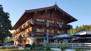 A traditional wooden building with balconies, a covered outdoor seating area, and a well-maintained lawn. - Landhotel Vordergrub (Kitzbuhel)