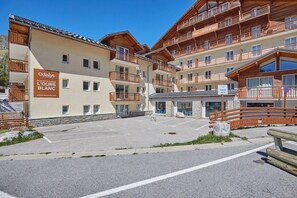 A multi-story hotel with wooden balconies and a sign indicating 'Odalys L'Ours Blanc.' - Studio abordable à 150m des remontées | Piscine (Les Deux Alpes)