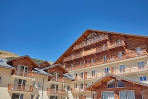 A multi-story wooden chalet with balconies and a clear sky. - Studio abordable à 150m des remontées | Piscine (Les Deux Alpes)