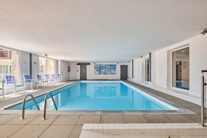 An indoor swimming pool with clear blue water, surrounded by white walls and a tiled floor. - Studio abordable à 150m des remontées | Piscine (Les Deux Alpes)