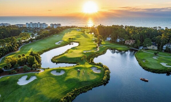 Ein Golfplatz mit Wasserhindernissen, einem Boot und Gebäuden im Hintergrund.