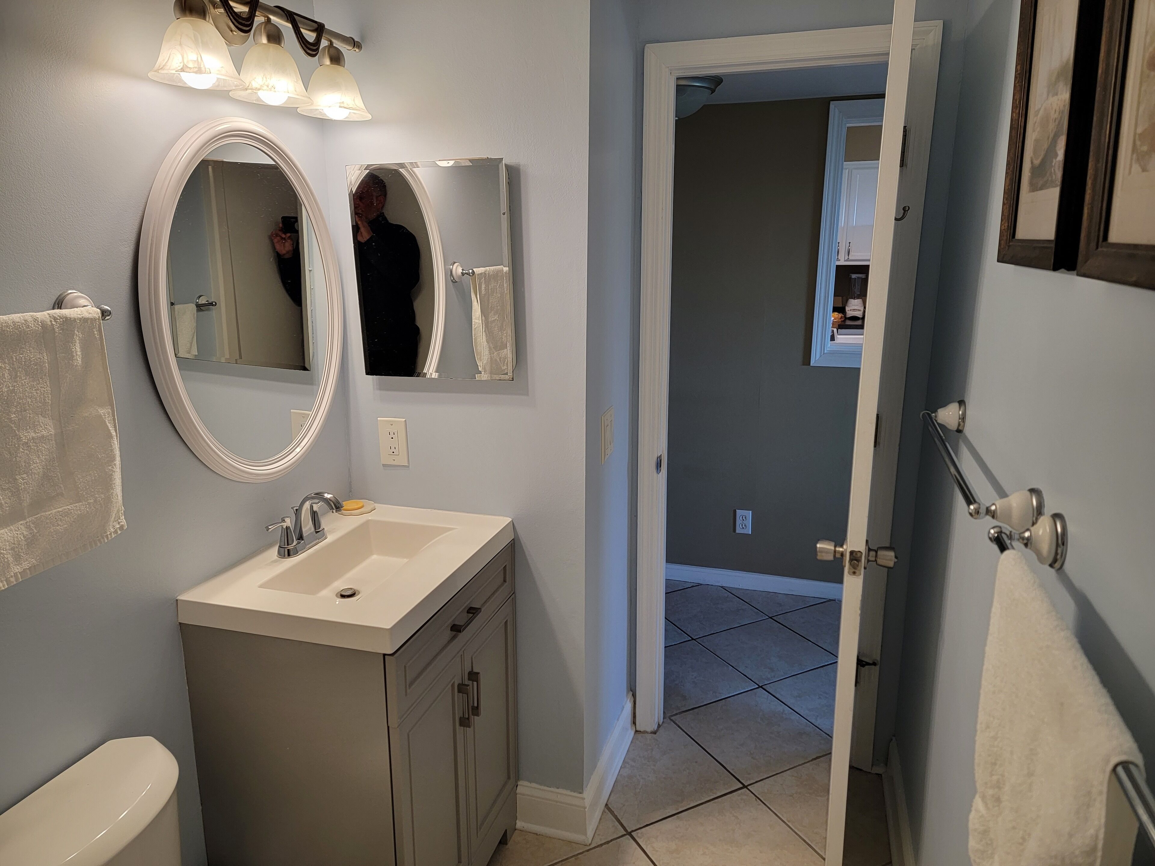 A bathroom with a vanity, sink, and two mirrors.