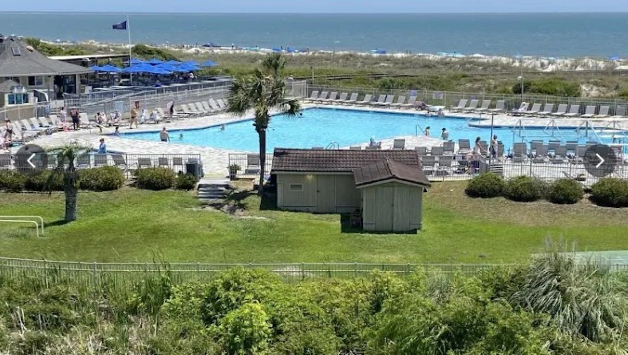 Un área de piscina con varias piscinas, sillas de descanso y un pequeño cobertizo.