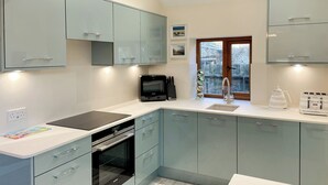 Una cocina moderna con armarios azul claro, horno empotrado, microondas y ventana con vista al exterior.